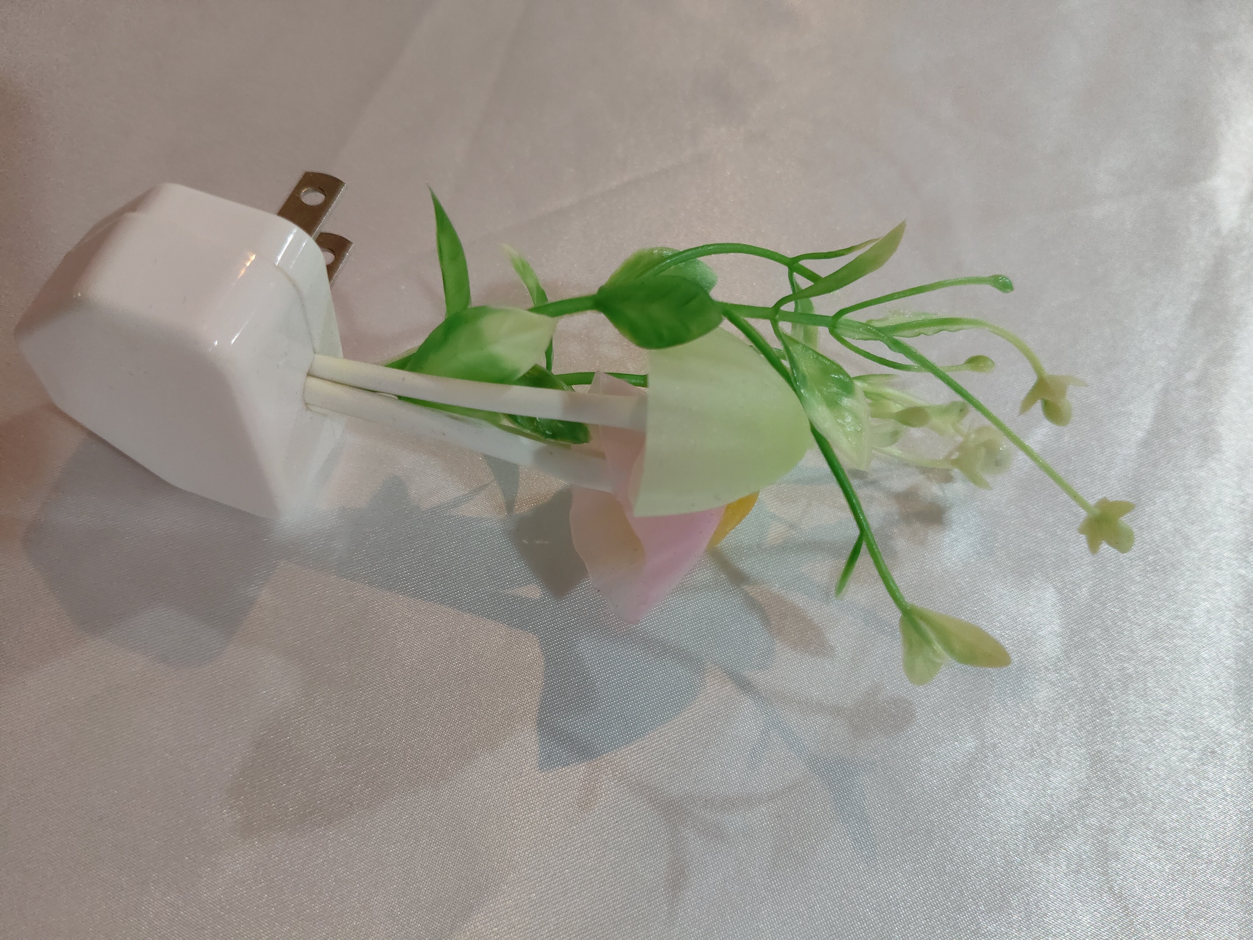 White electronic device with green leaves on a light gray background